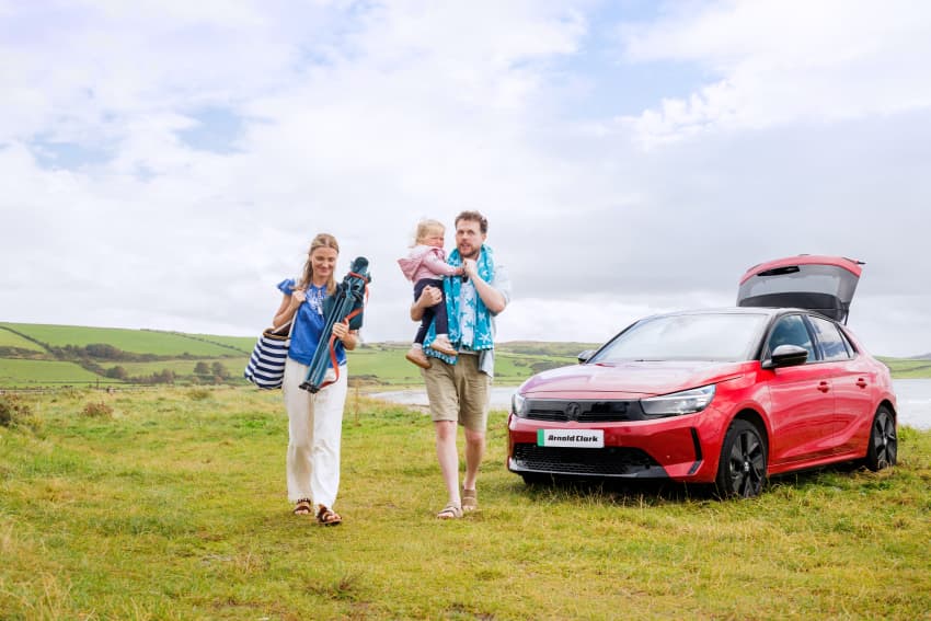 Family beside parked Vauxhall Corsa by the seaside