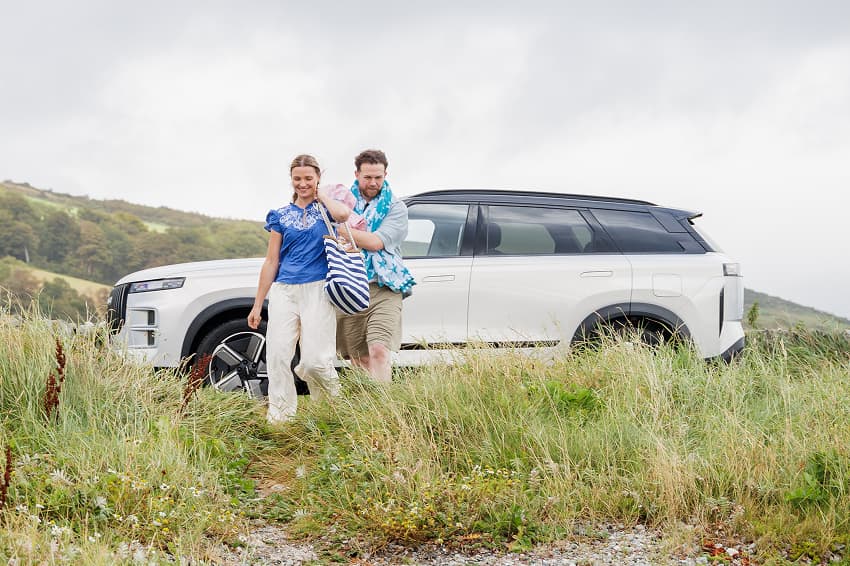 Young family beside a JAECOO 7 at the seaside