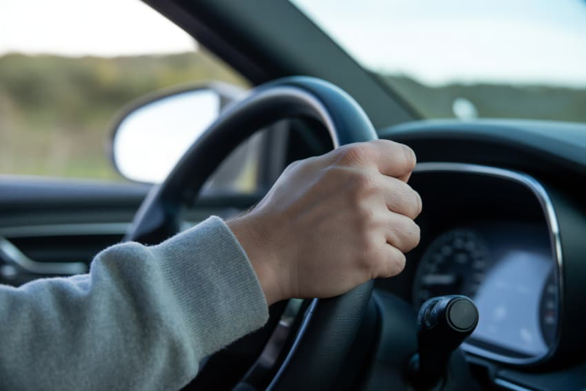 Close-up of persons hand on steering wheel