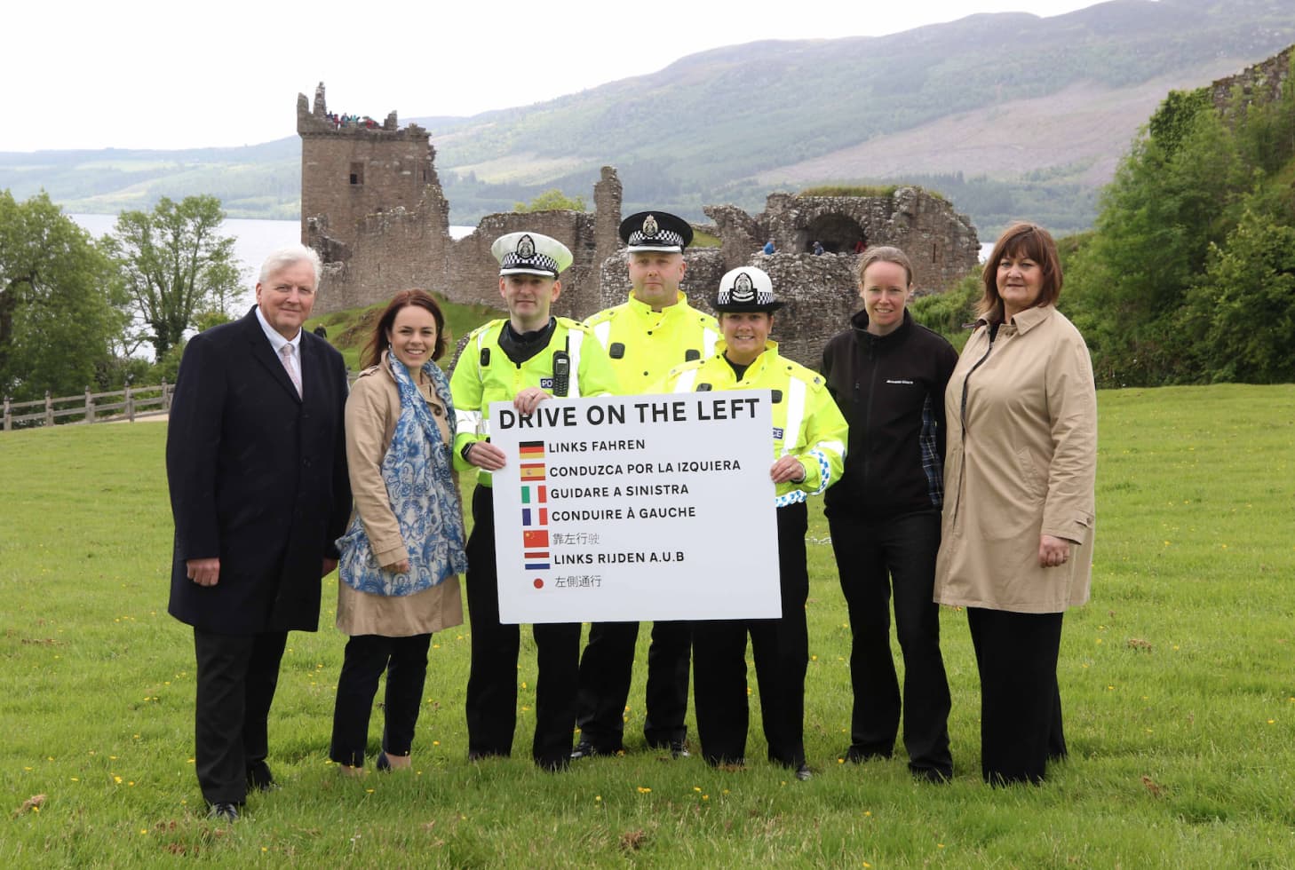 Group of people holding a sign saying drive on the left